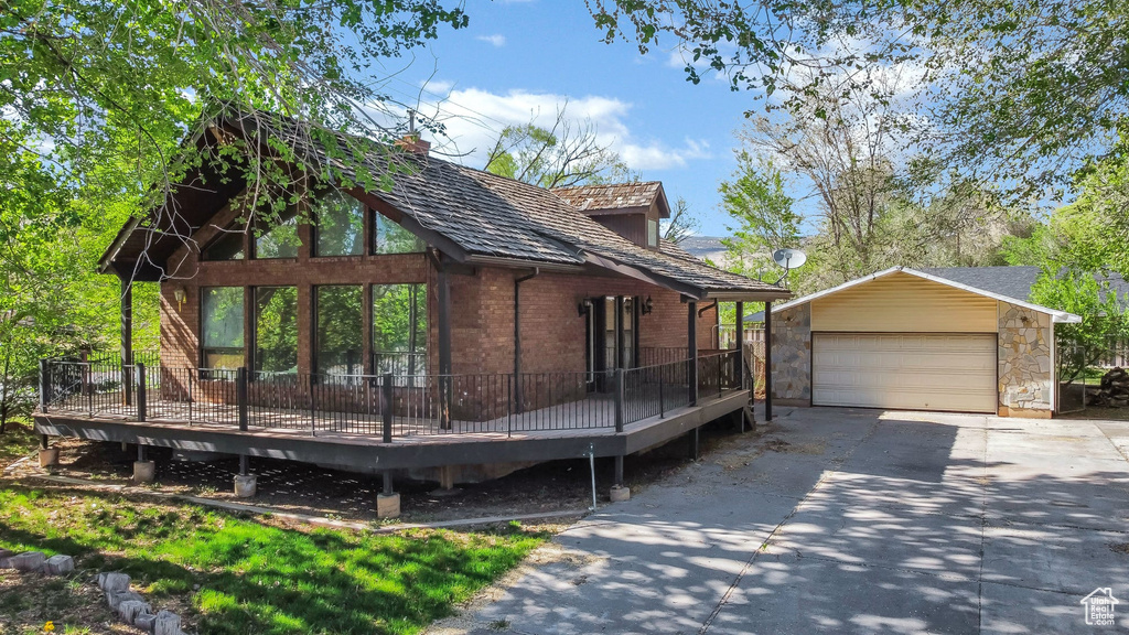 View of side of property featuring an outbuilding, a wooden deck, a garage, and brick siding