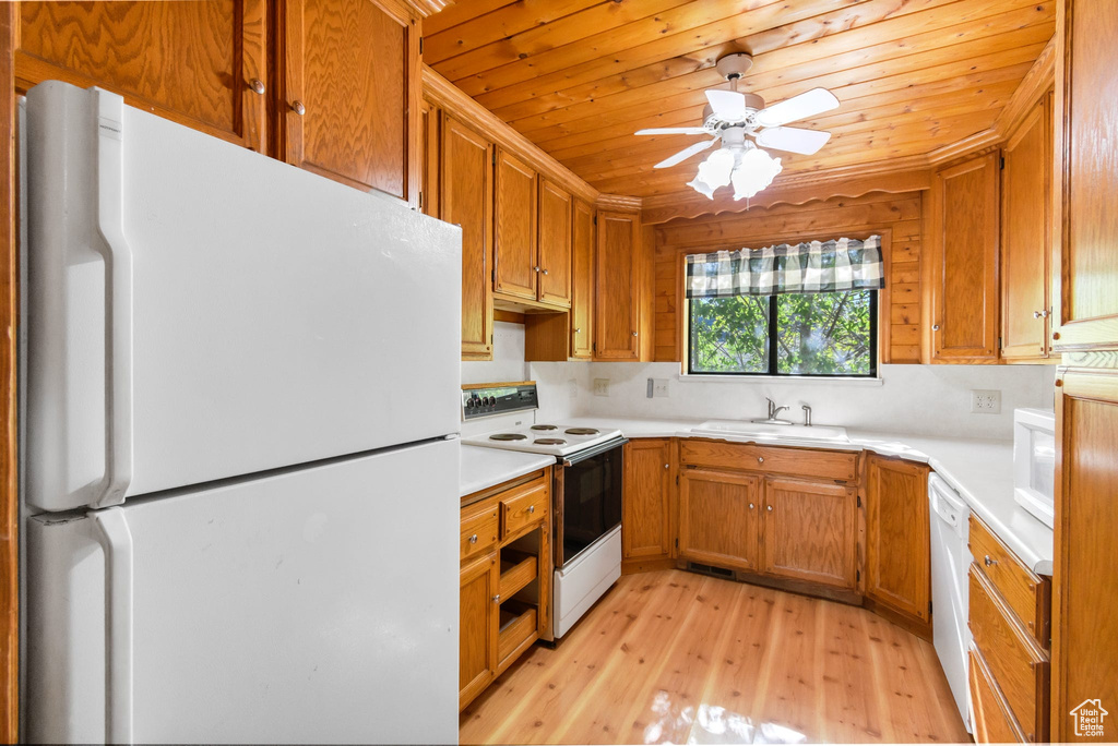 Kitchen featuring white appliances, a sink, light wood finished floors, light countertops, and wood ceiling