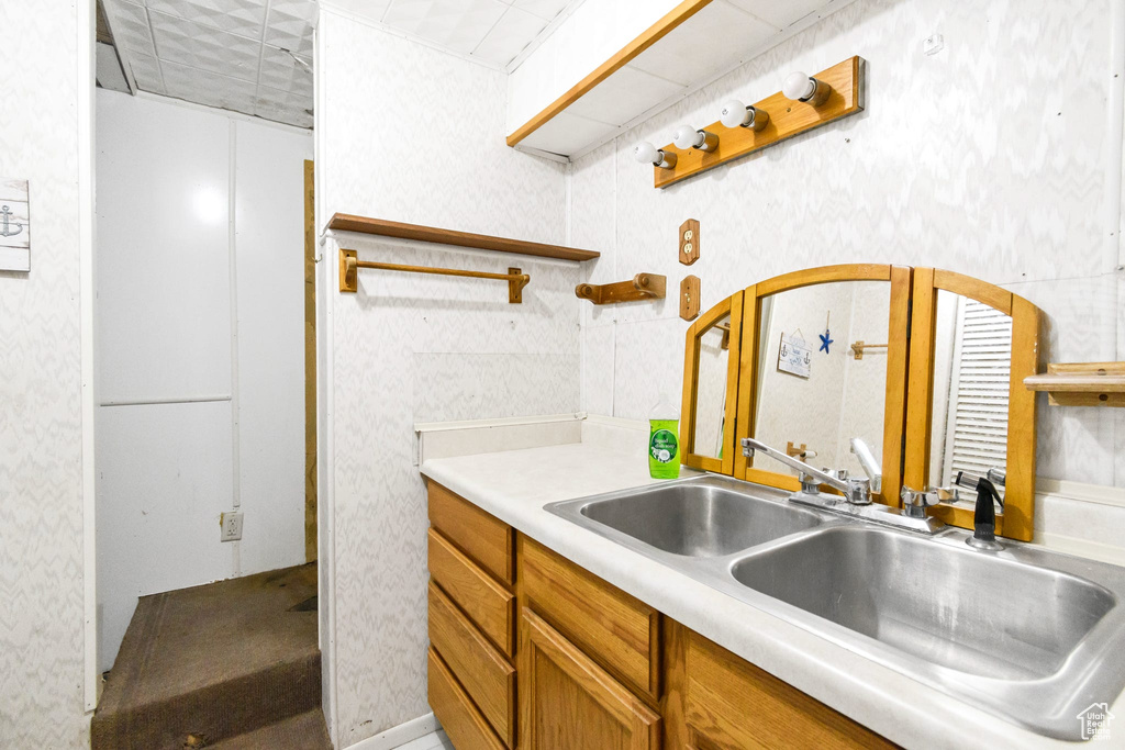Kitchen featuring open shelves, a sink, light countertops, brown cabinetry, and wallpapered walls