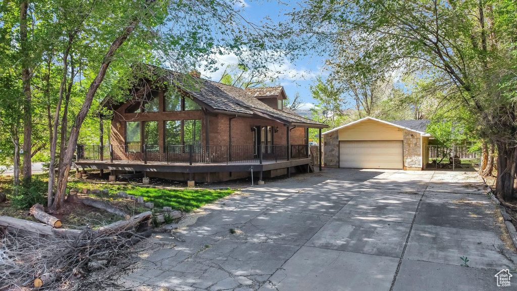 View of home\'s exterior featuring an outdoor structure, a wooden deck, brick siding, a garage, and driveway