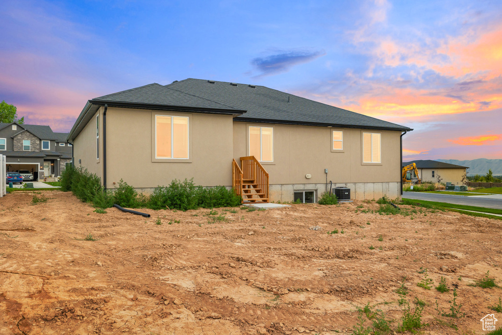 Back of house at dusk featuring a shingled roof