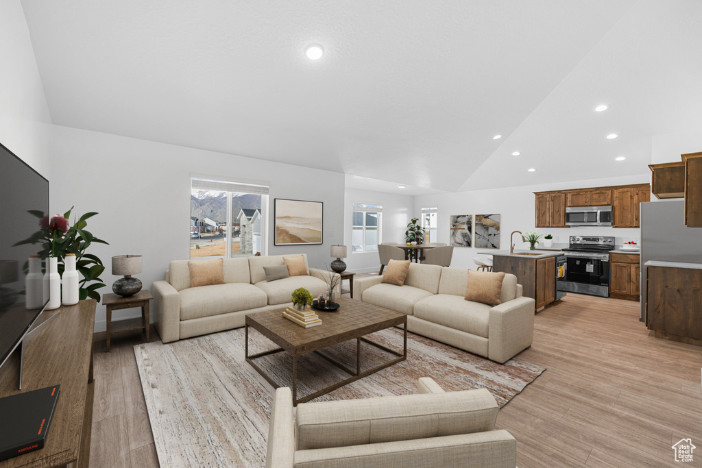 Living room featuring vaulted ceiling, recessed lighting, and light wood-style floors