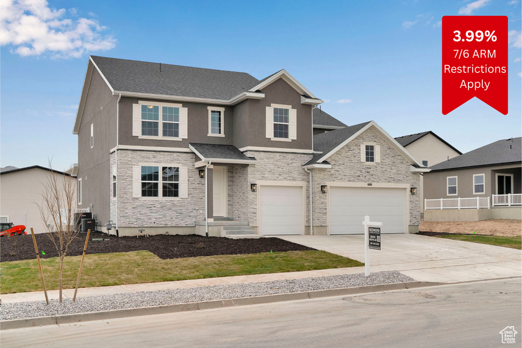 Traditional-style home featuring stone siding, driveway, a garage, and stucco siding