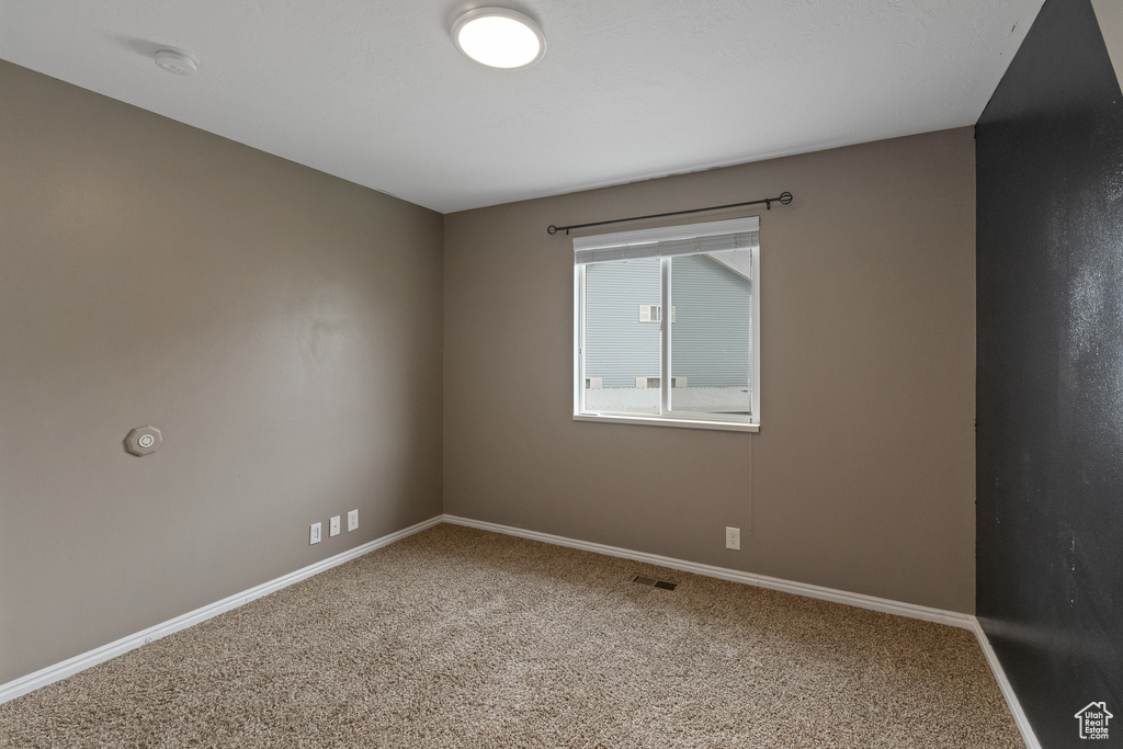 Carpeted spare room featuring visible vents and baseboards