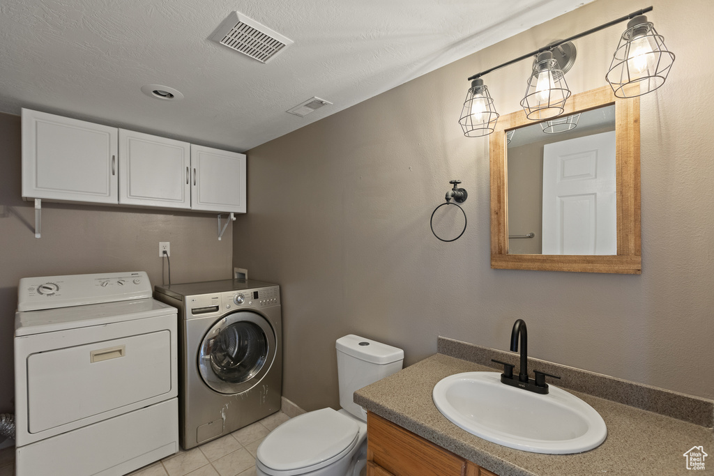 Half bath with toilet, visible vents, independent washer and dryer, and vanity