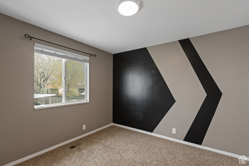 Carpeted spare room with visible vents and baseboards