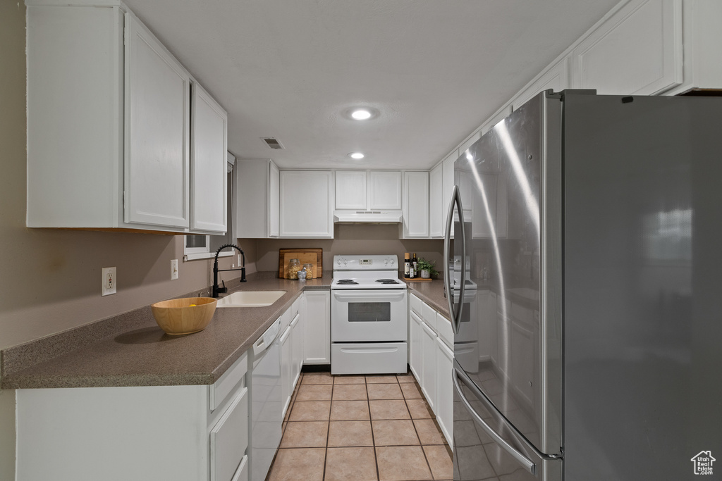 Kitchen featuring visible vents, a sink, white appliances, white cabinetry, and light tile patterned flooring
