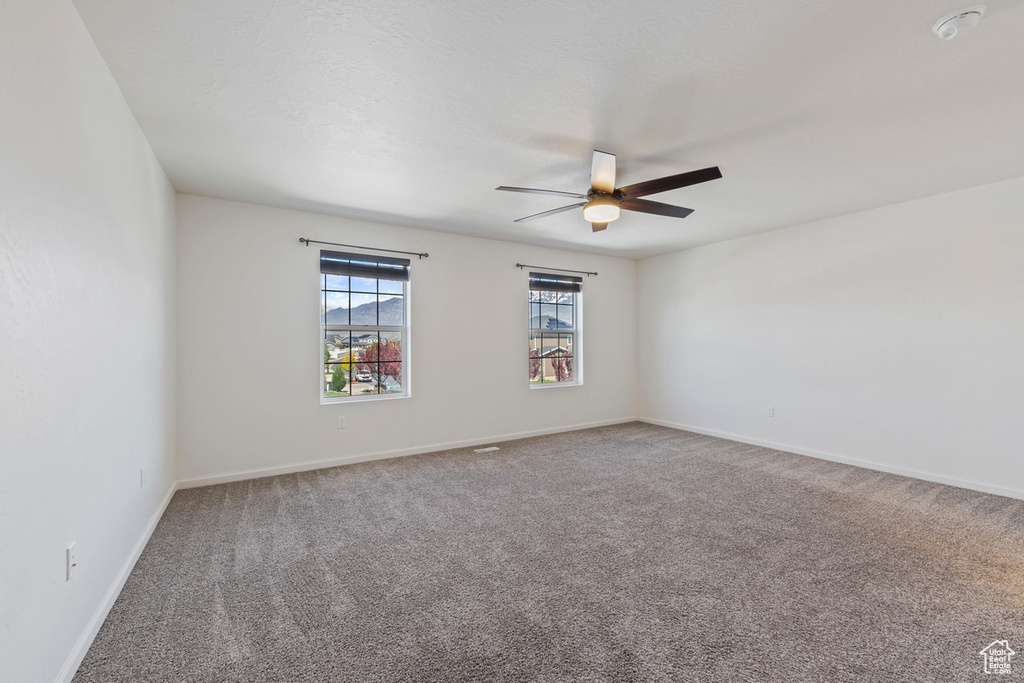 Unfurnished room featuring carpet floors, a ceiling fan, and baseboards