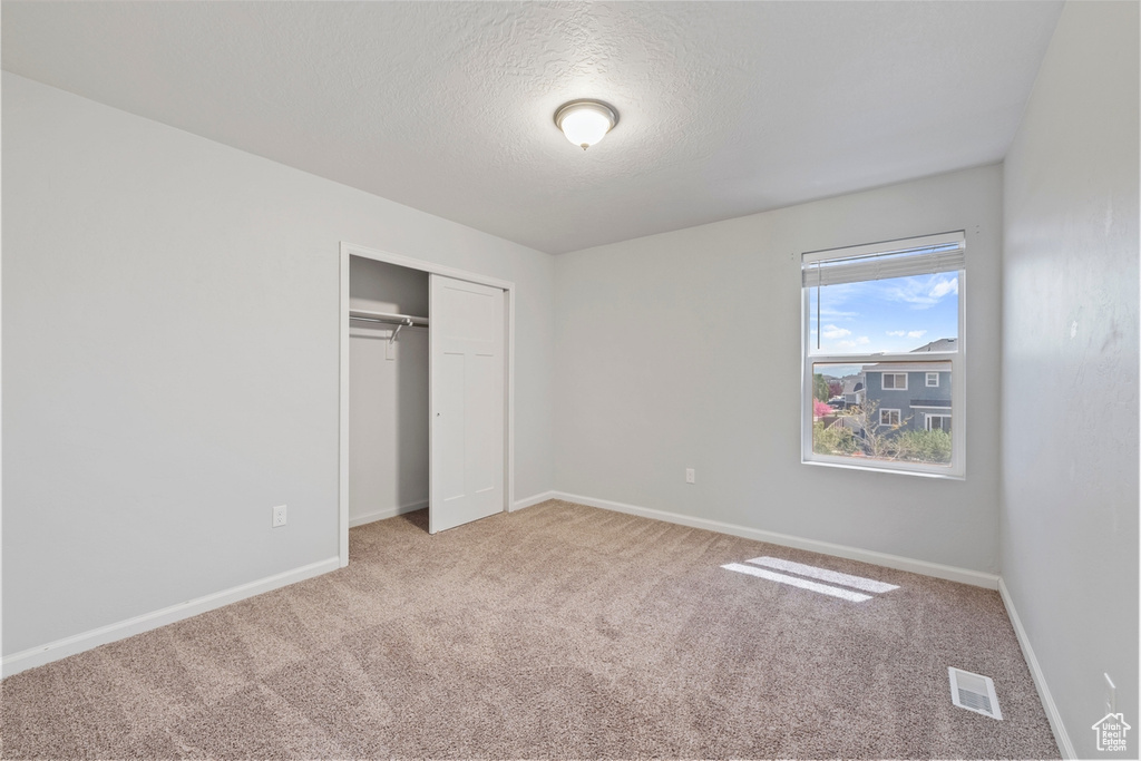 Unfurnished bedroom with carpet floors, baseboards, a closet, and visible vents
