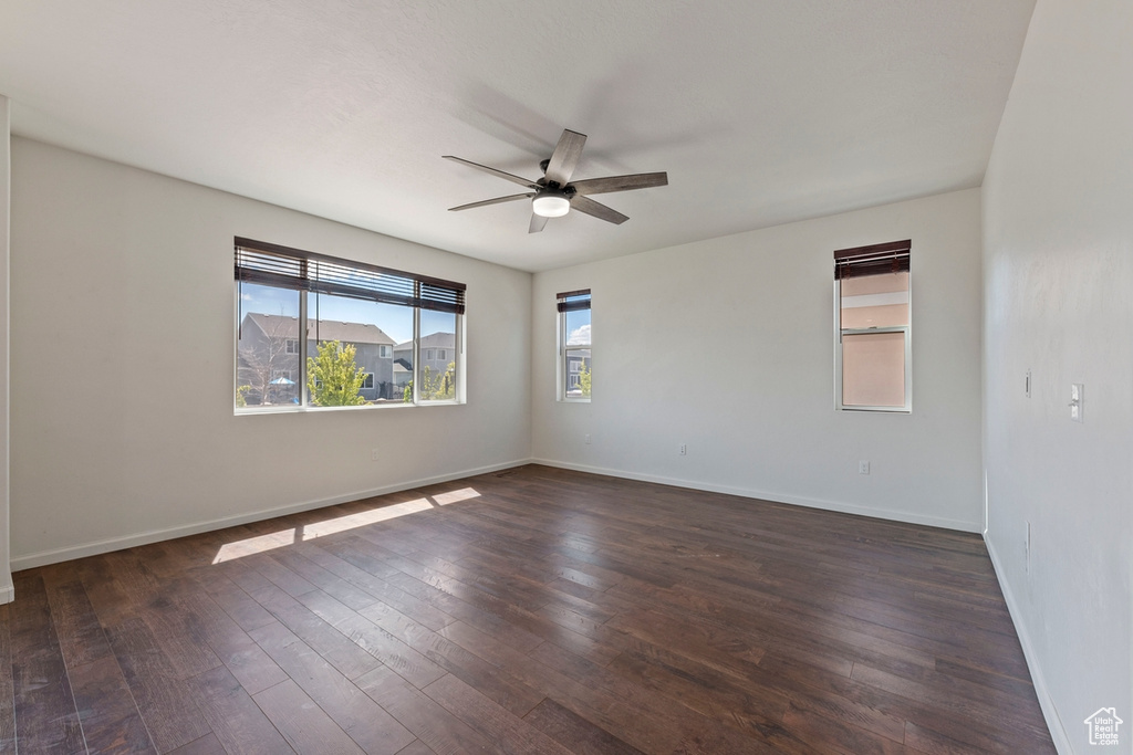 Spare room featuring baseboards, a ceiling fan, and dark wood finished floors