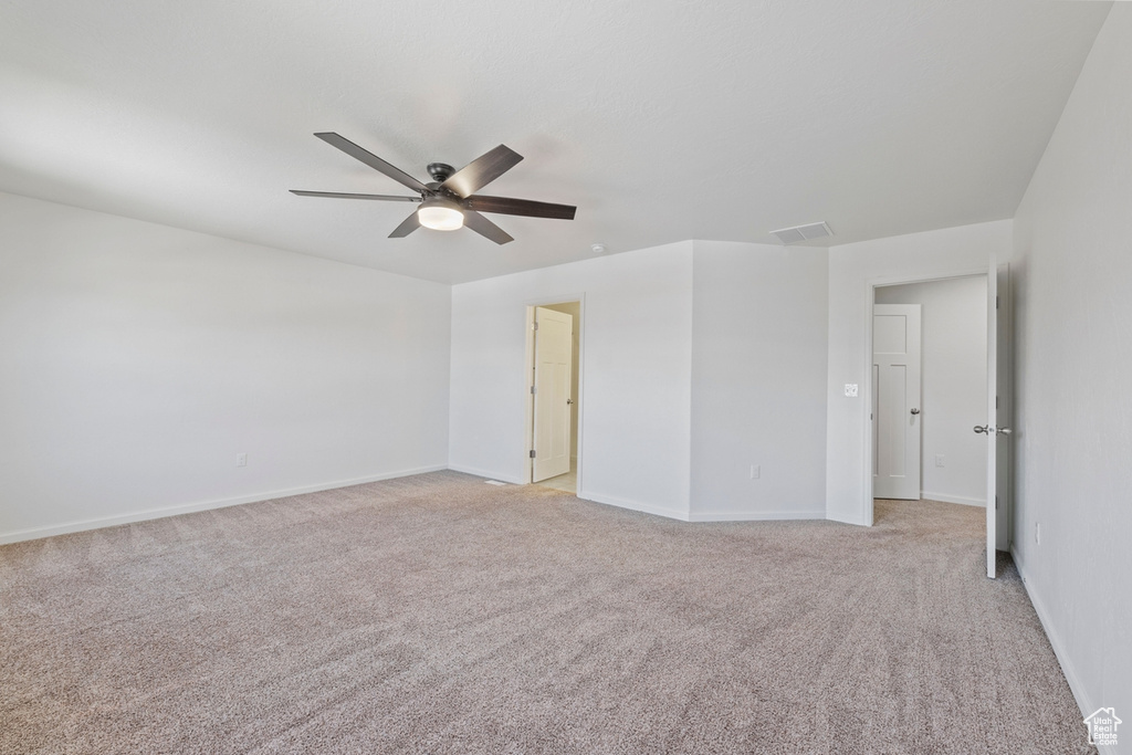 Empty room featuring a ceiling fan, baseboards, visible vents, and light carpet