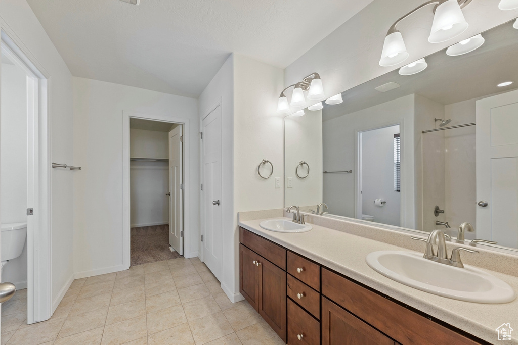 Full bathroom featuring double vanity, toilet, baseboards, and a sink