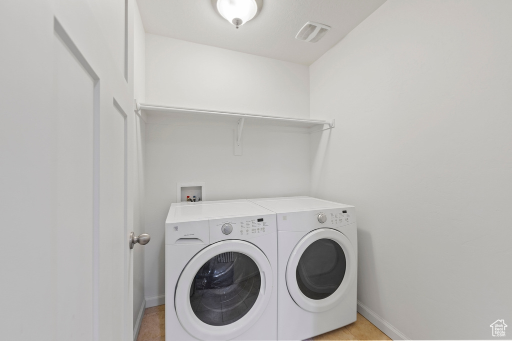 Clothes washing area with laundry area, visible vents, washing machine and dryer, and baseboards