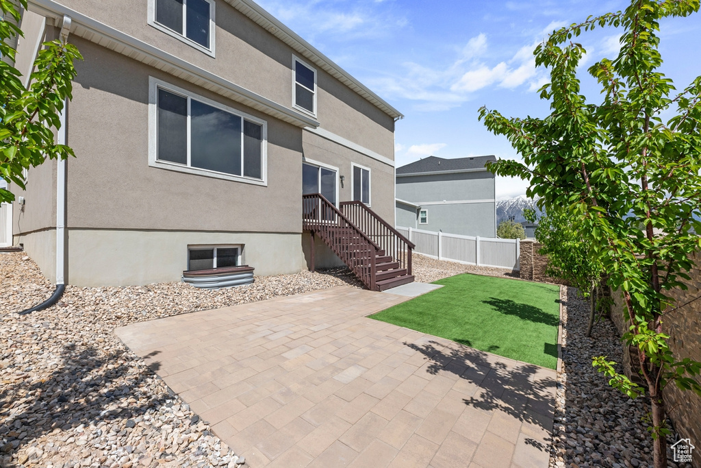 Rear view of property featuring fence, a patio, stucco siding, and a lawn