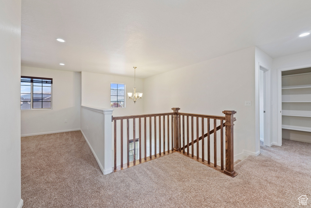 Hallway featuring an inviting chandelier, carpet, and an upstairs landing