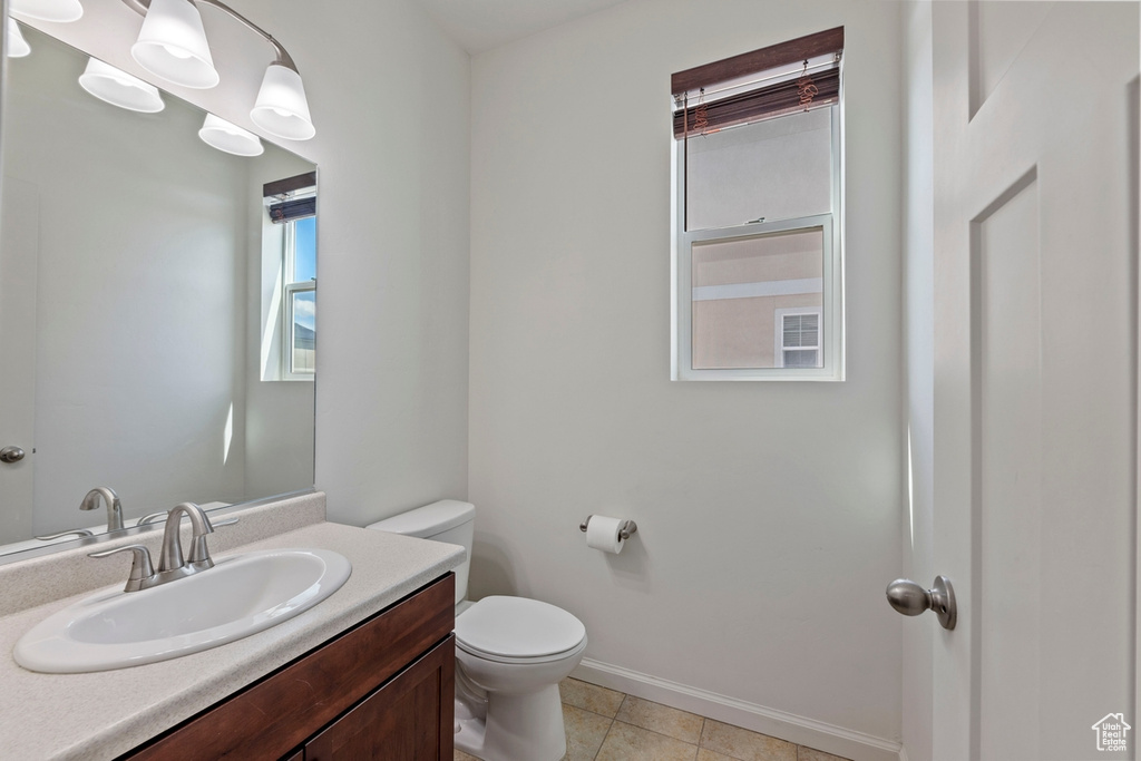Bathroom featuring baseboards, tile patterned floors, toilet, and vanity