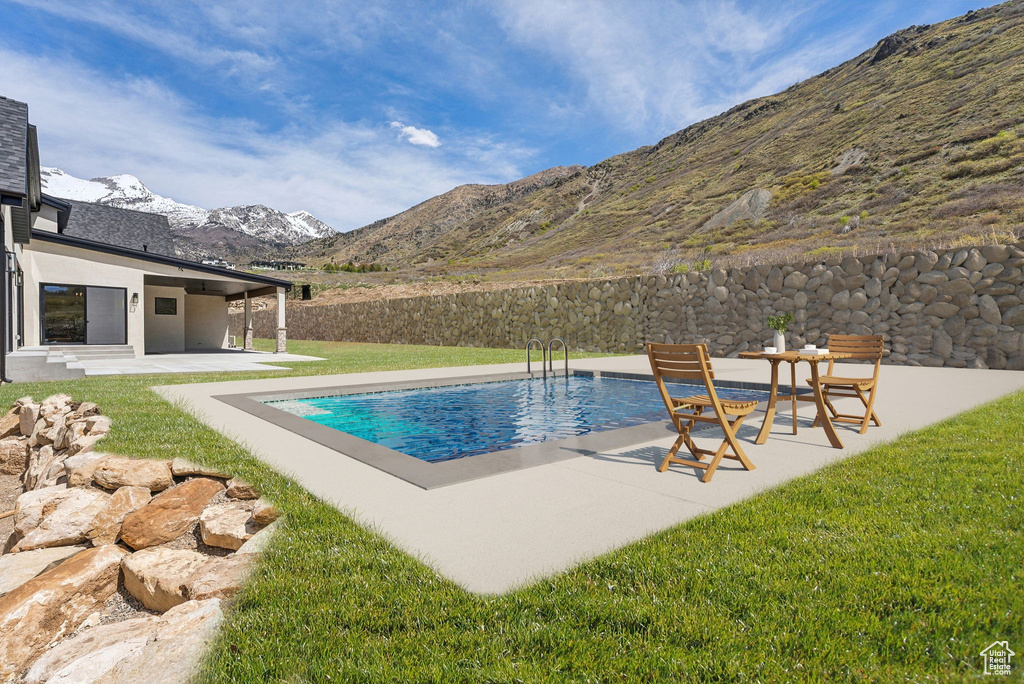 View of pool featuring a mountain view, a patio area, a lawn, and a fenced in pool