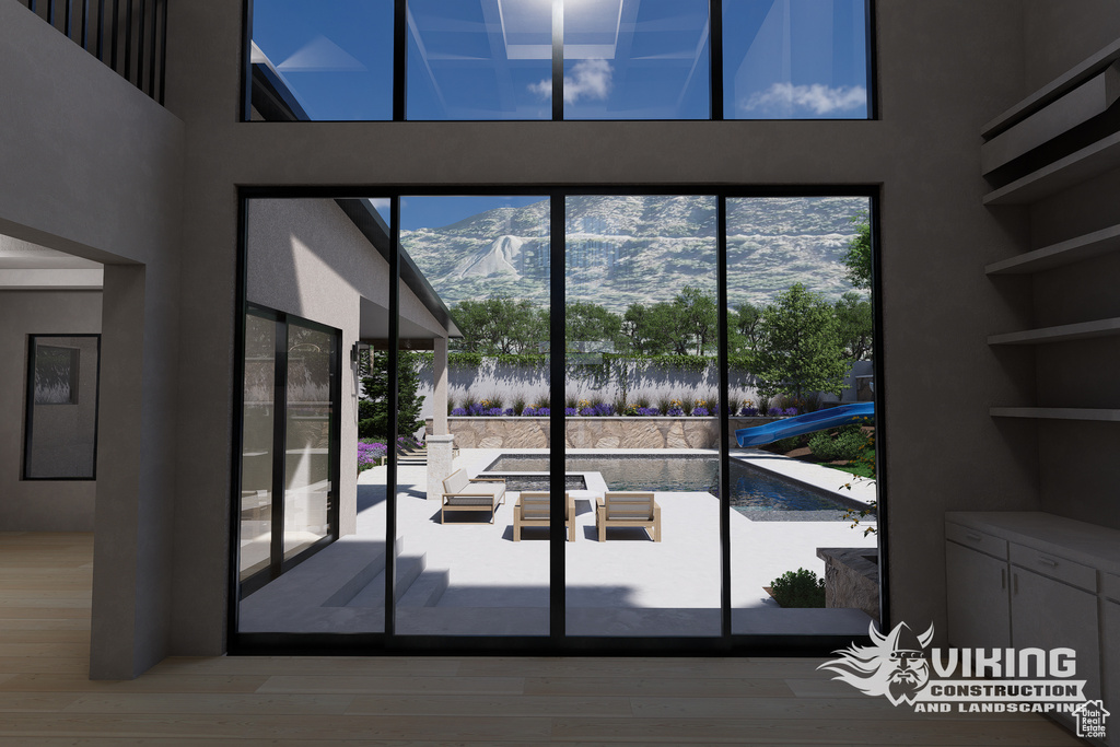 Entryway with healthy amount of natural light, wood finished floors, a mountain view, and a high ceiling