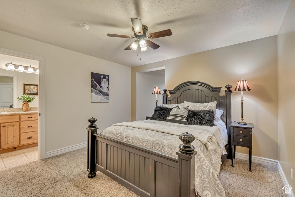 Bedroom with ensuite bathroom, ceiling fan, baseboards, and light colored carpet