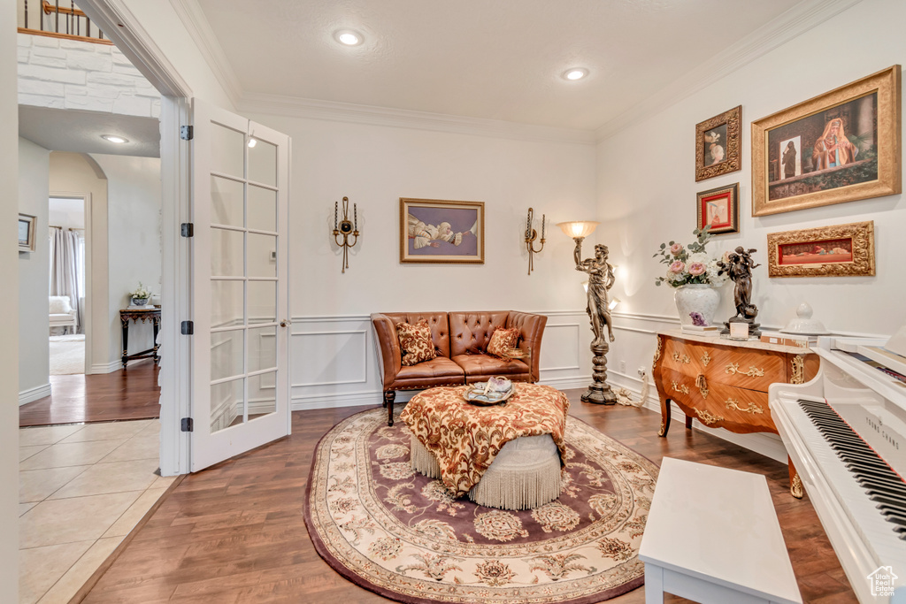Living area with a wainscoted wall, a decorative wall, crown molding, wood finished floors, and arched walkways
