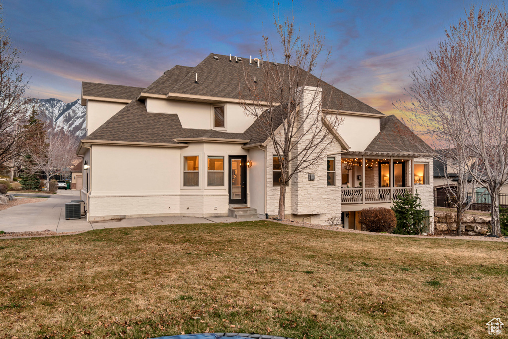 Rear view of property featuring roof with shingles, central air condition unit, stucco siding, a pergola, and a yard