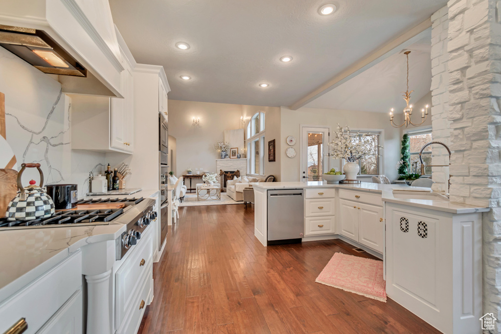 Kitchen with dark wood finished floors, white cabinets, a peninsula, and appliances with stainless steel finishes