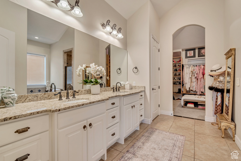 Full bath featuring a spacious closet, tile patterned flooring, a sink, and double vanity