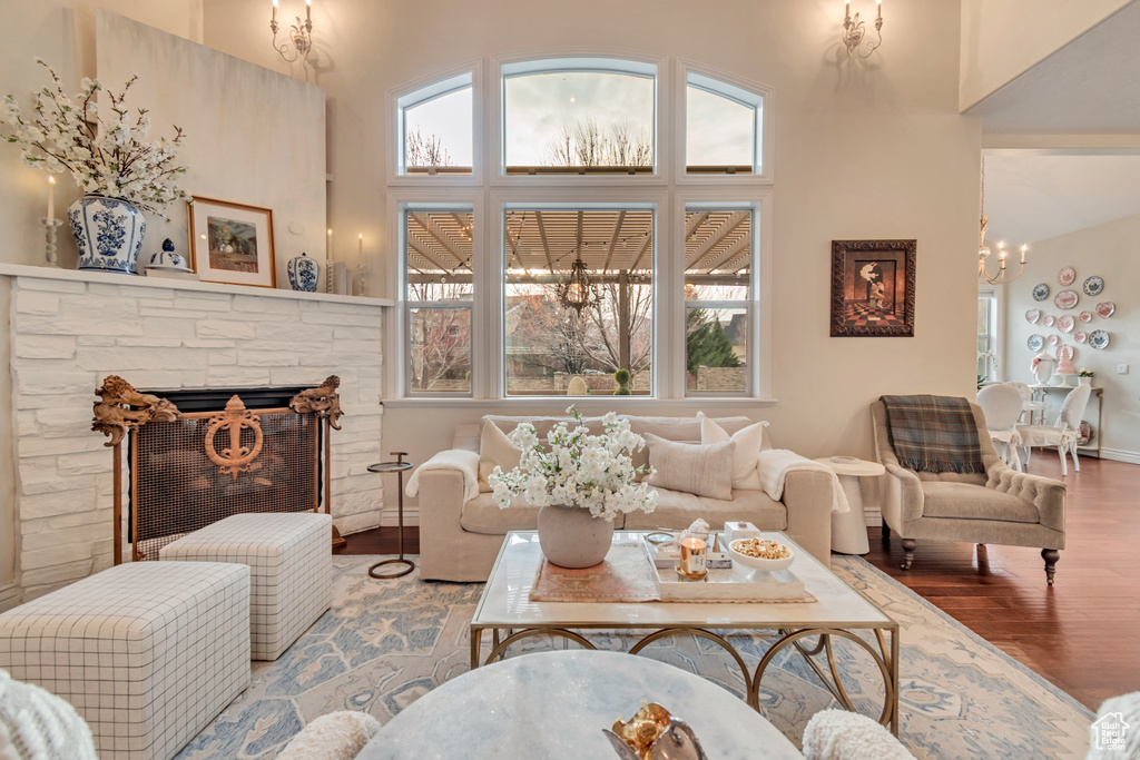 Living room with a high ceiling, wood finished floors, a notable chandelier, and plenty of natural light