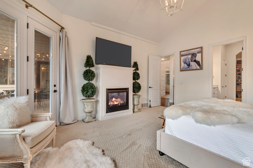 Bedroom with connected bathroom, vaulted ceiling, carpet flooring, a glass covered fireplace, and visible vents