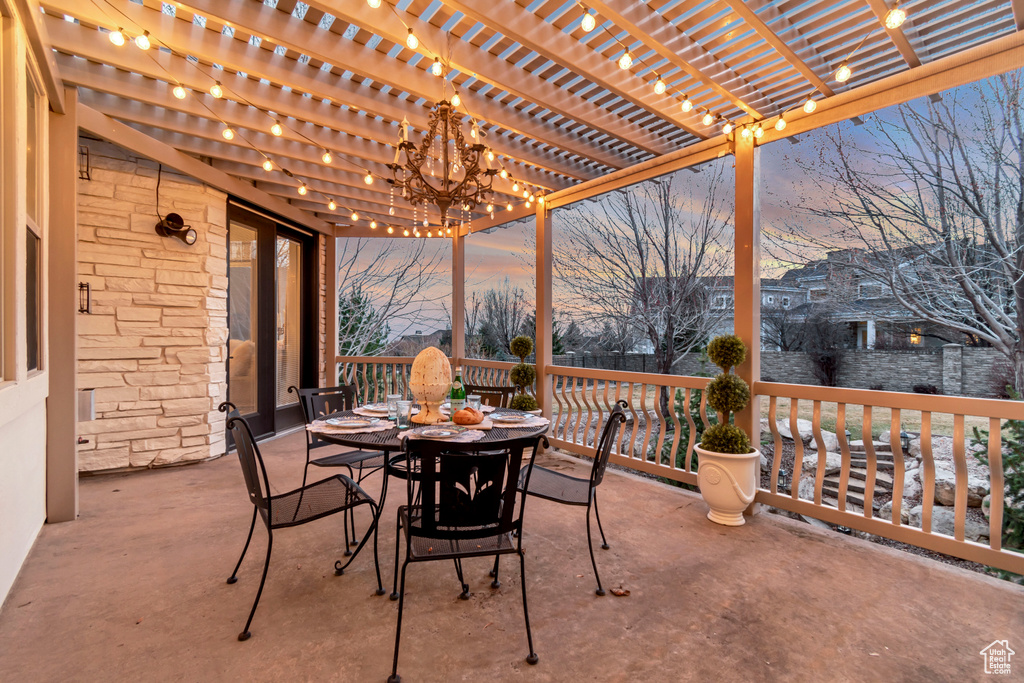 Patio terrace at dusk featuring outdoor dining area and a pergola