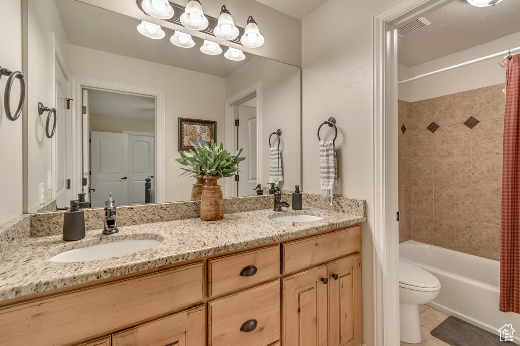 Bathroom with toilet, a sink, double vanity, and shower / bath combo