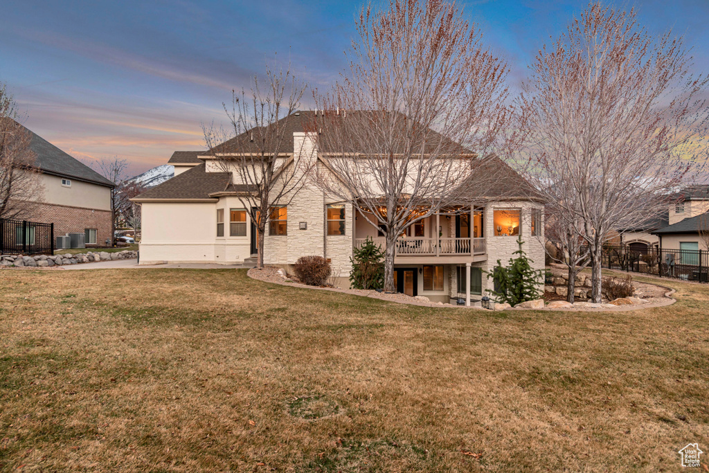 Back of house with a lawn, stucco siding, and fence