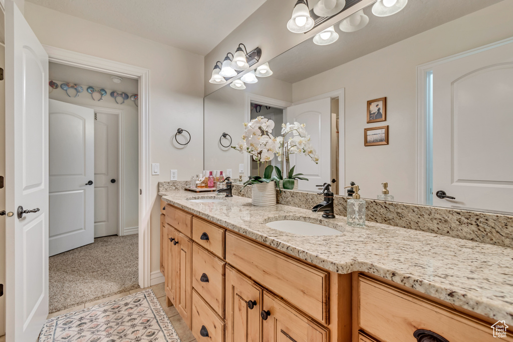 Bathroom with baseboards, double vanity, a sink, and tile patterned floors