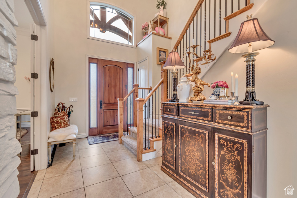 Entryway featuring a high ceiling, light tile patterned floors, and stairway