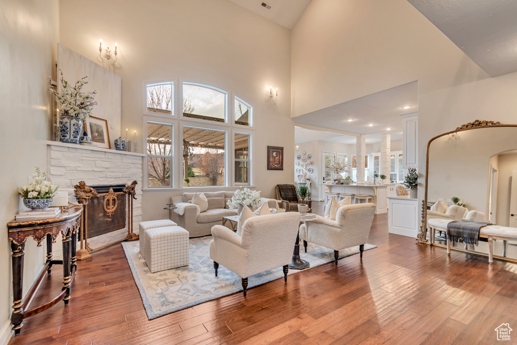 Living room featuring a fireplace, a high ceiling, arched walkways, and hardwood / wood-style flooring