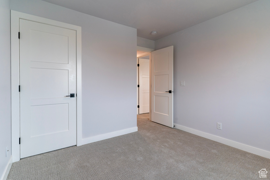 Unfurnished bedroom with baseboards and light colored carpet