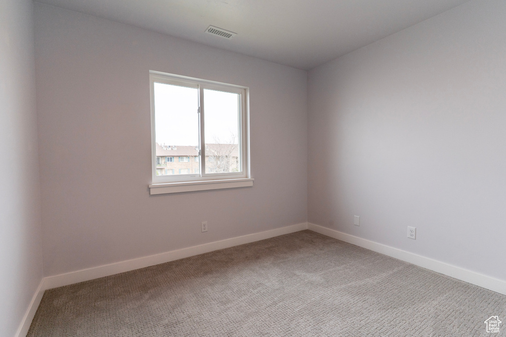 Spare room featuring baseboards, light colored carpet, and visible vents