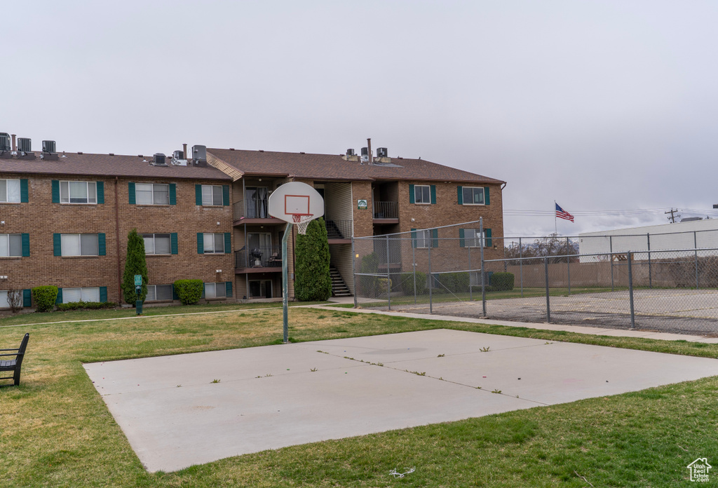 Exterior space featuring community basketball court, fence, and a lawn