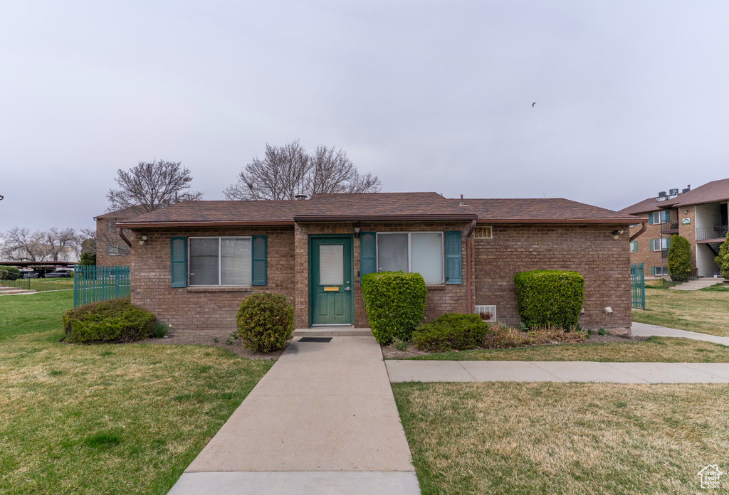View of front facade featuring a front lawn, a shingled roof, and brick siding