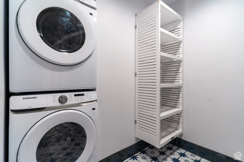 Laundry area featuring baseboards, stacked washer and clothes dryer, and laundry area