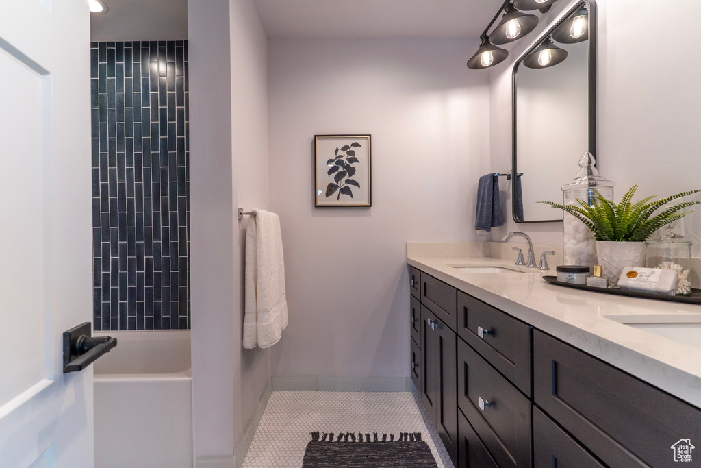 Bathroom with double vanity, a sink, tile patterned floors, and baseboards