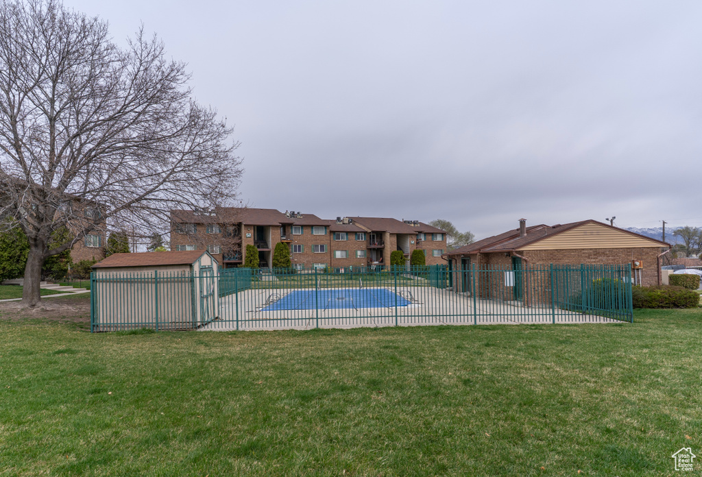 Pool with an outdoor structure, a yard, fence, and a patio area