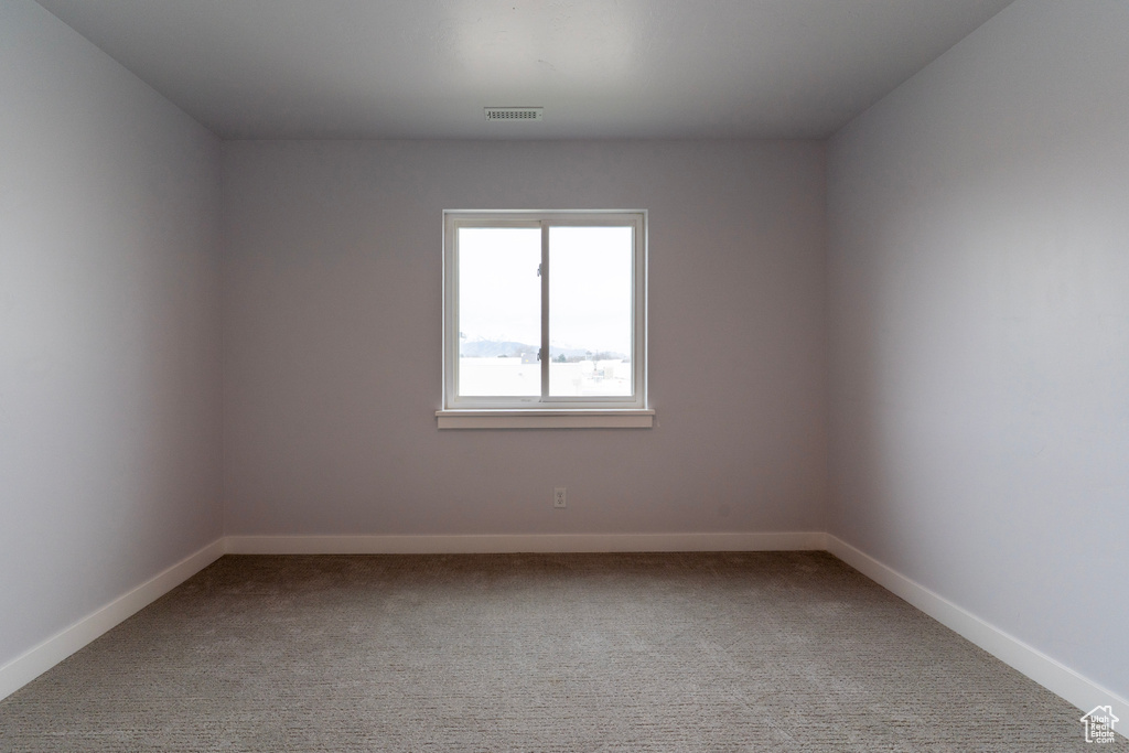 Carpeted empty room with baseboards and visible vents