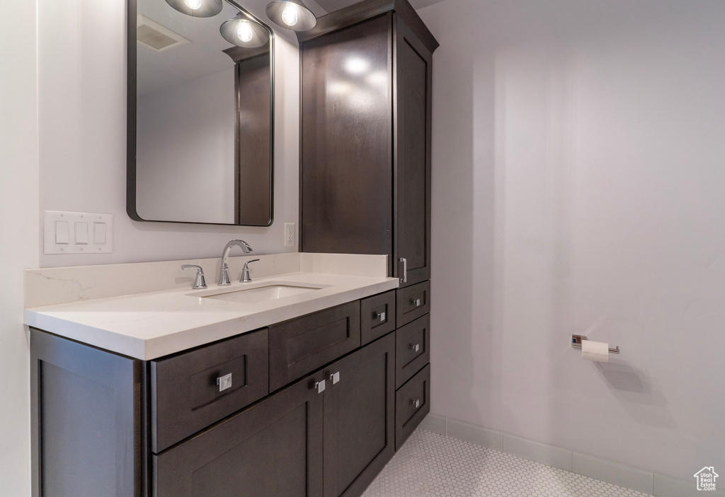 Bathroom with baseboards, tile patterned floors, and vanity