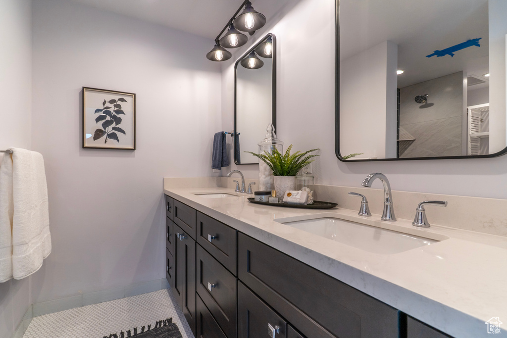 Bathroom featuring double vanity, a sink, baseboards, and walk in shower
