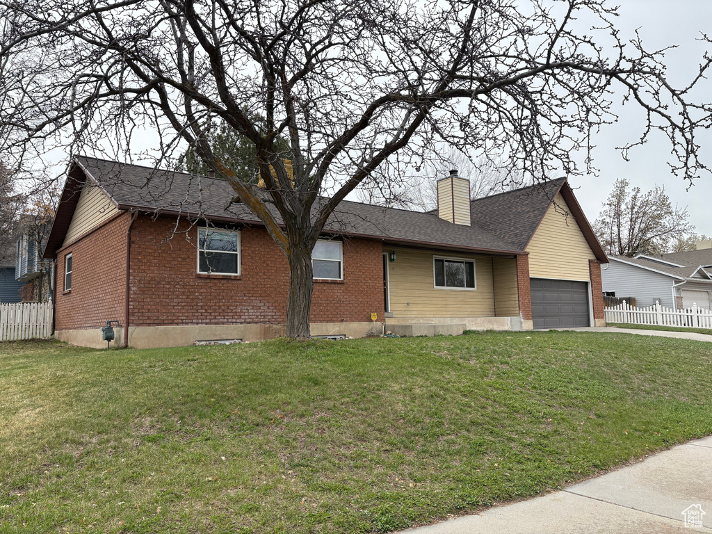 Single story home featuring a front lawn, an attached garage, fence, and brick siding