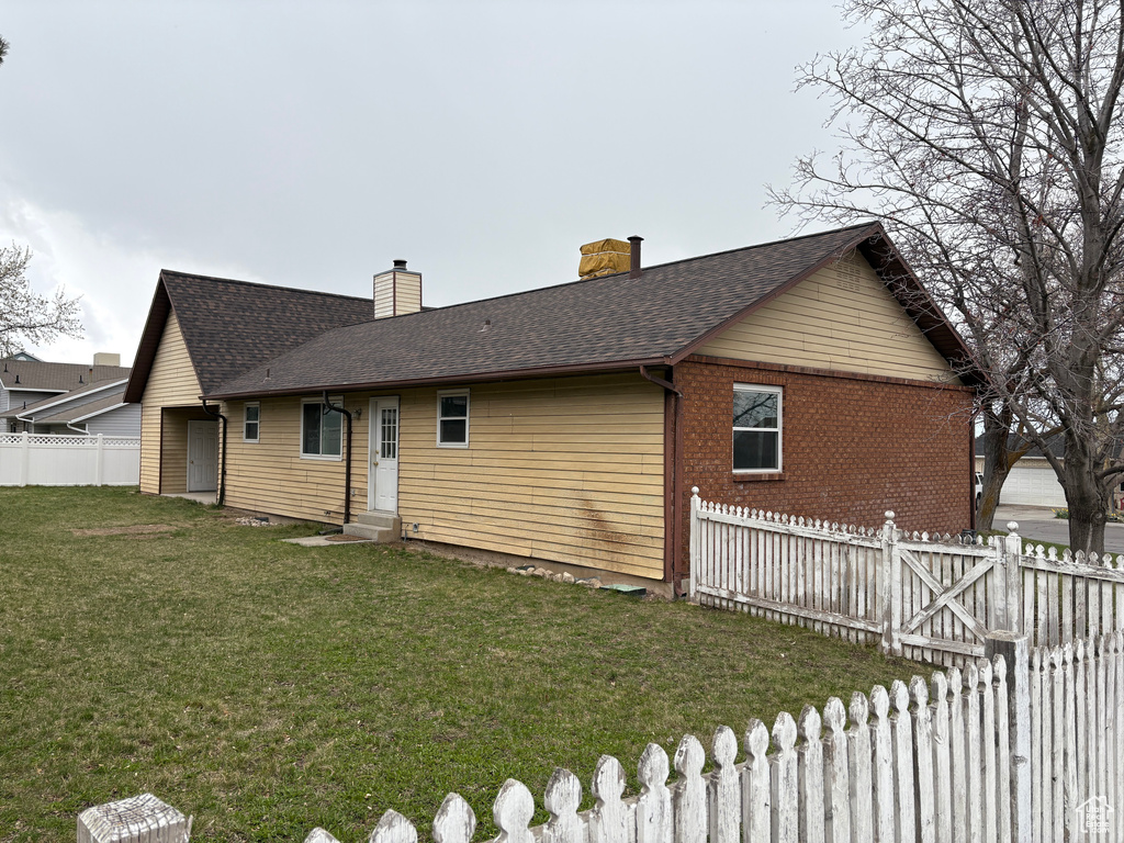 Exterior space featuring fence, entry steps, a chimney, a front yard, and roof with shingles