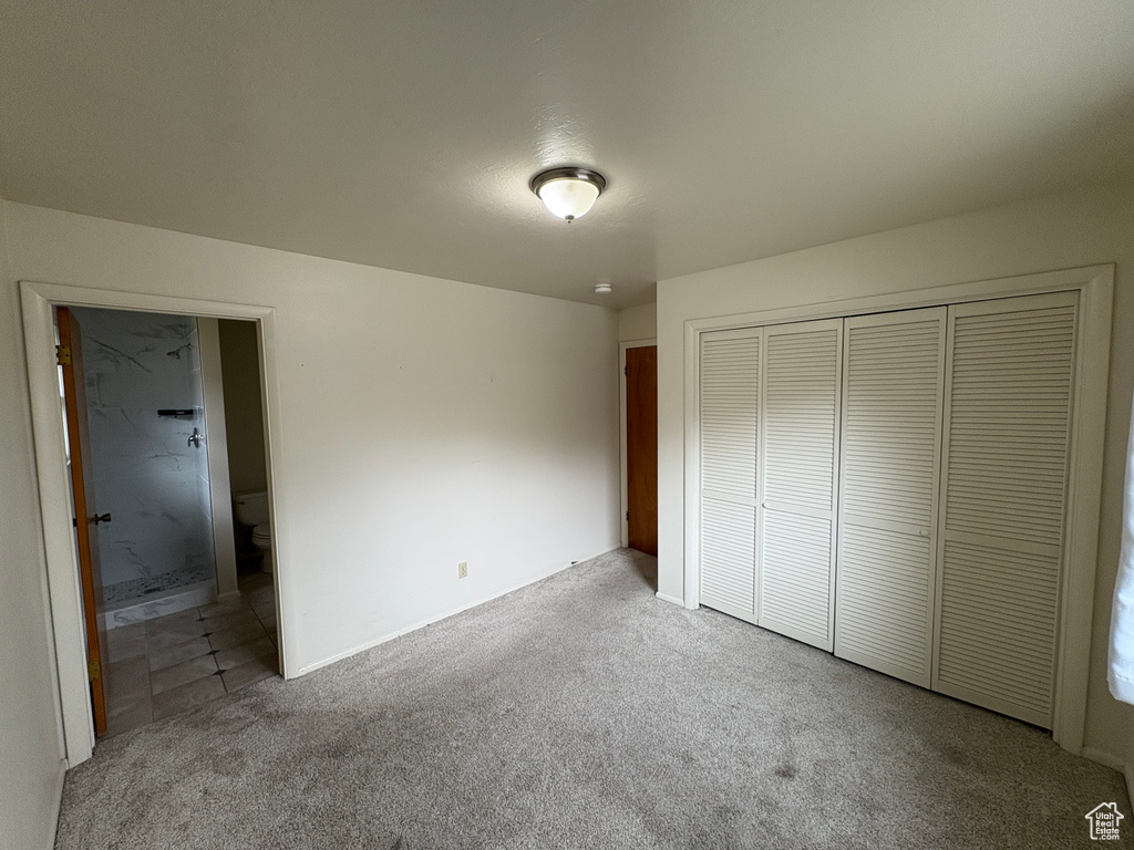 Unfurnished bedroom featuring carpet floors, connected bathroom, and a closet