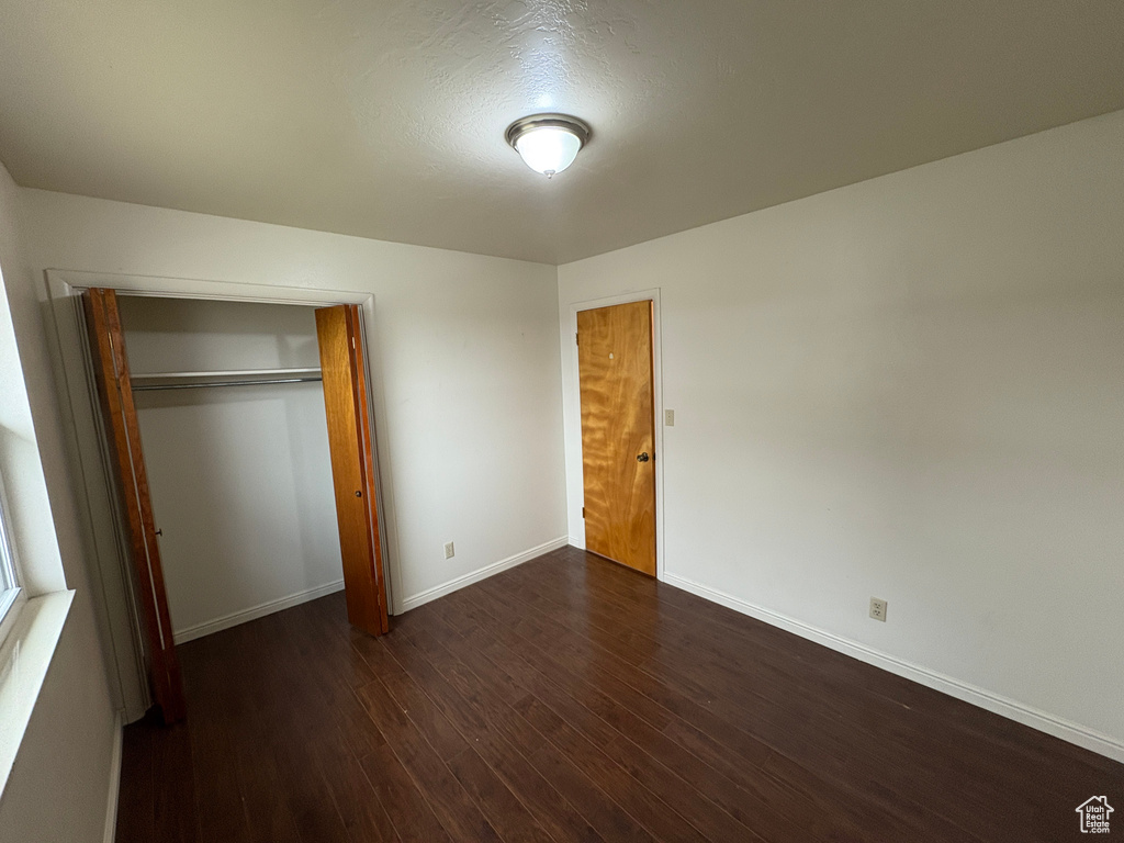 Unfurnished bedroom with baseboards, a closet, and wood finished floors