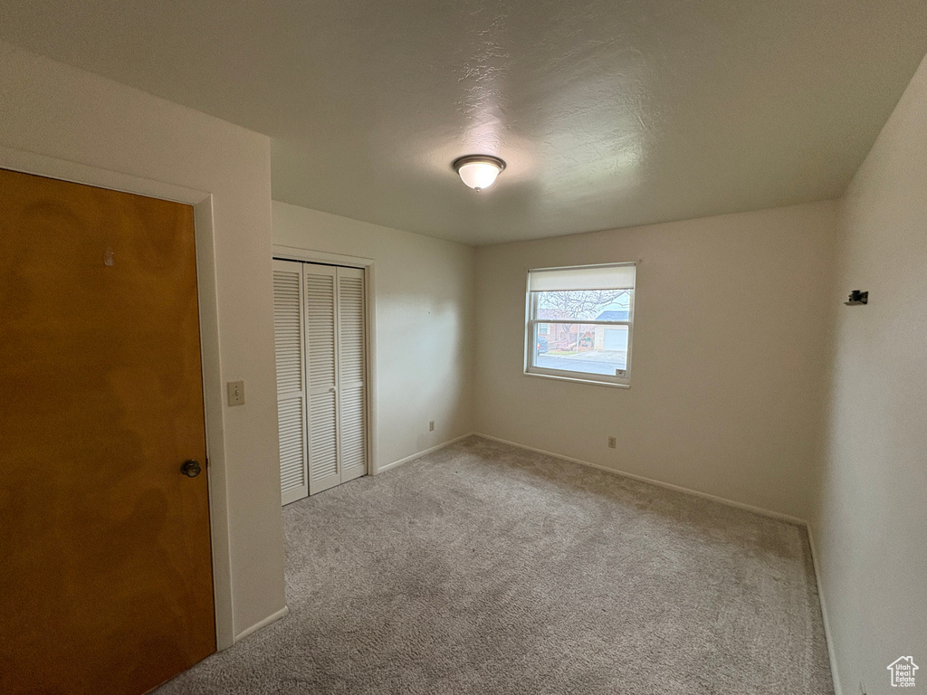 Unfurnished bedroom featuring a closet, carpet floors, and baseboards